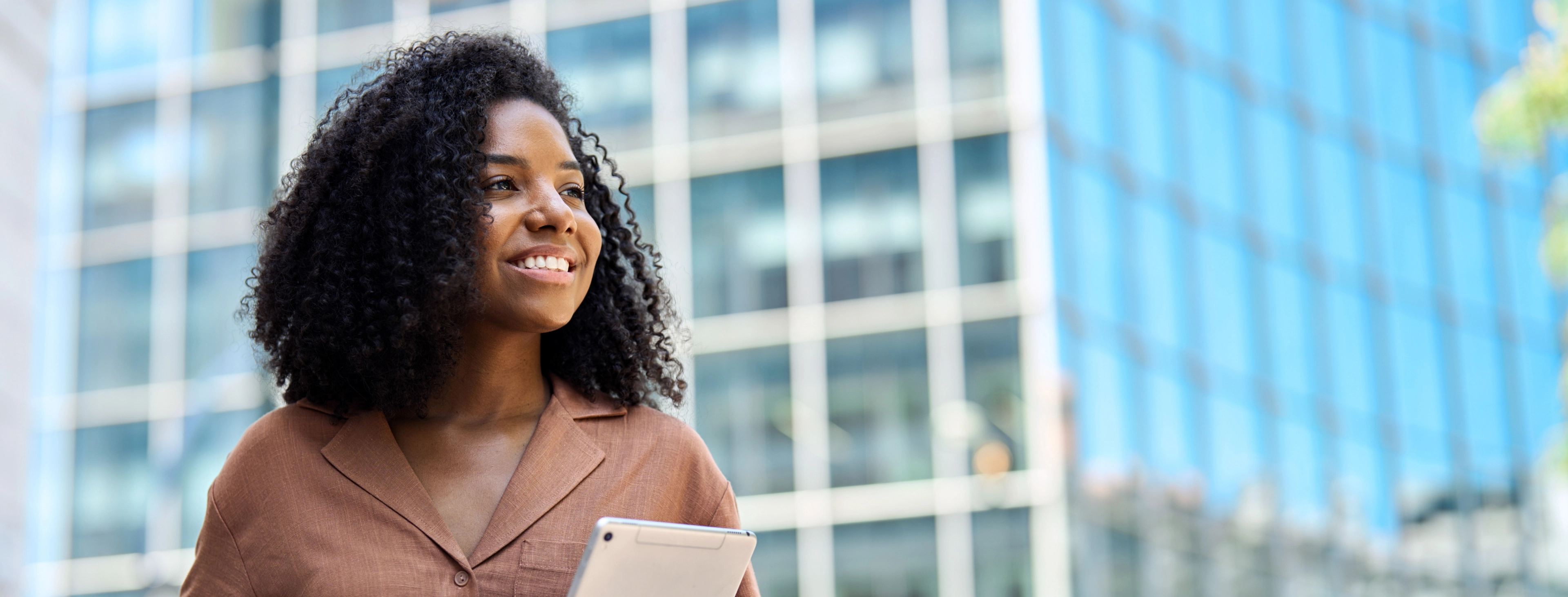 Smiling professional woman with tablet outdoors representing intelligent business and AI transformation