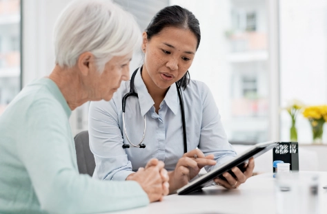 Doctor showing medical information on a digital tablet to a senior patient during a consultation