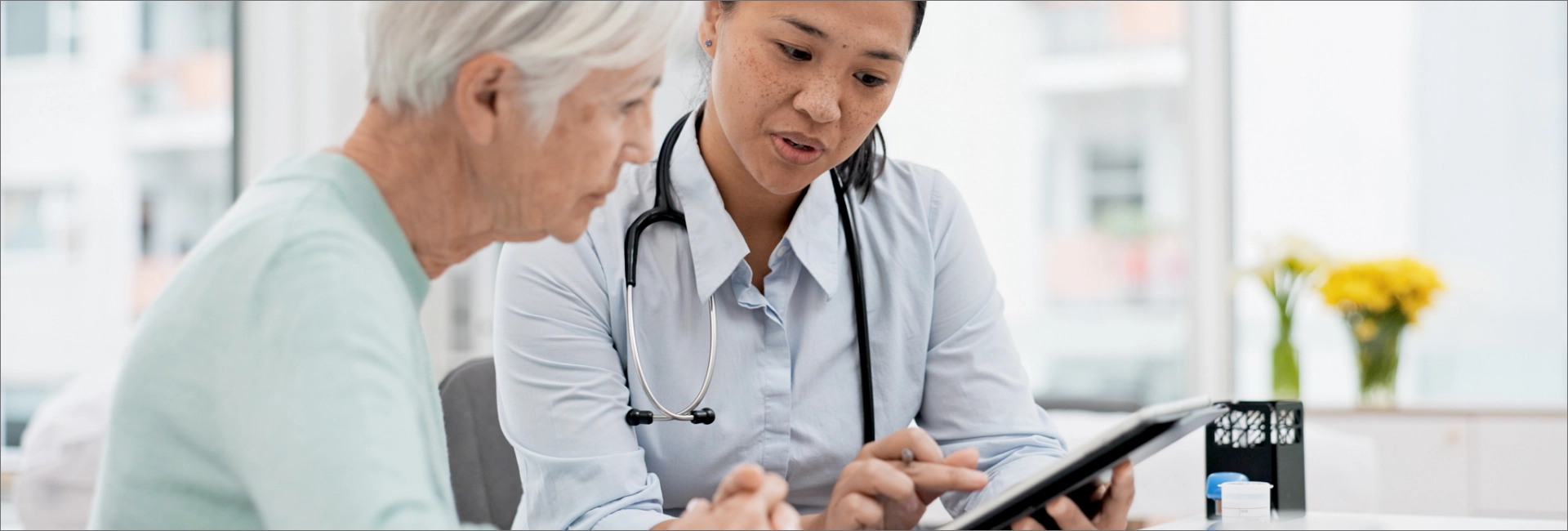 Doctor showing medical information on a digital tablet to a senior patient during a consultation