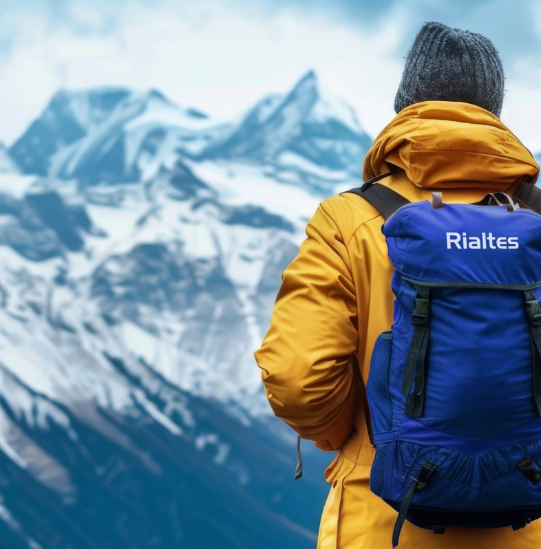 Hiker with Rialtes backpack facing snowy mountain peaks representing company culture values and daily growth mindset journey