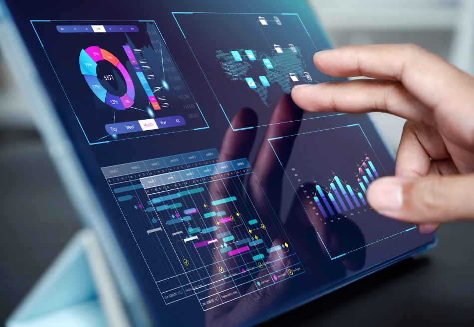 Hand holding transparent card with financial charts over tablet displaying colorful interactive dashboard analytics