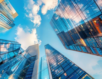 Modern glass skyscrapers looking upward with blue sky showcasing Exelona real estate finance Salesforce FSC solution