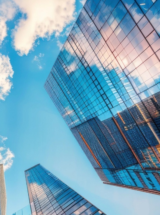 Modern glass skyscrapers reflecting blue sky and clouds viewed from below showcasing contemporary corporate architecture