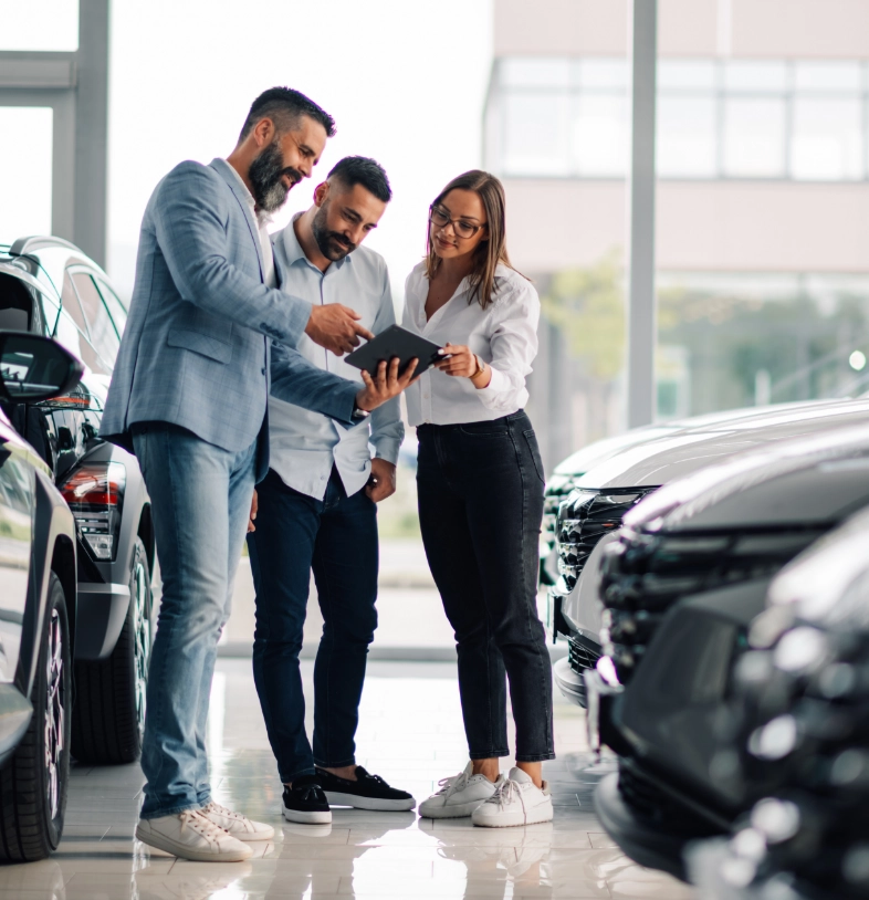 Automotive professionals consulting with tablet in modern dealership discussing industry solutions and challenges