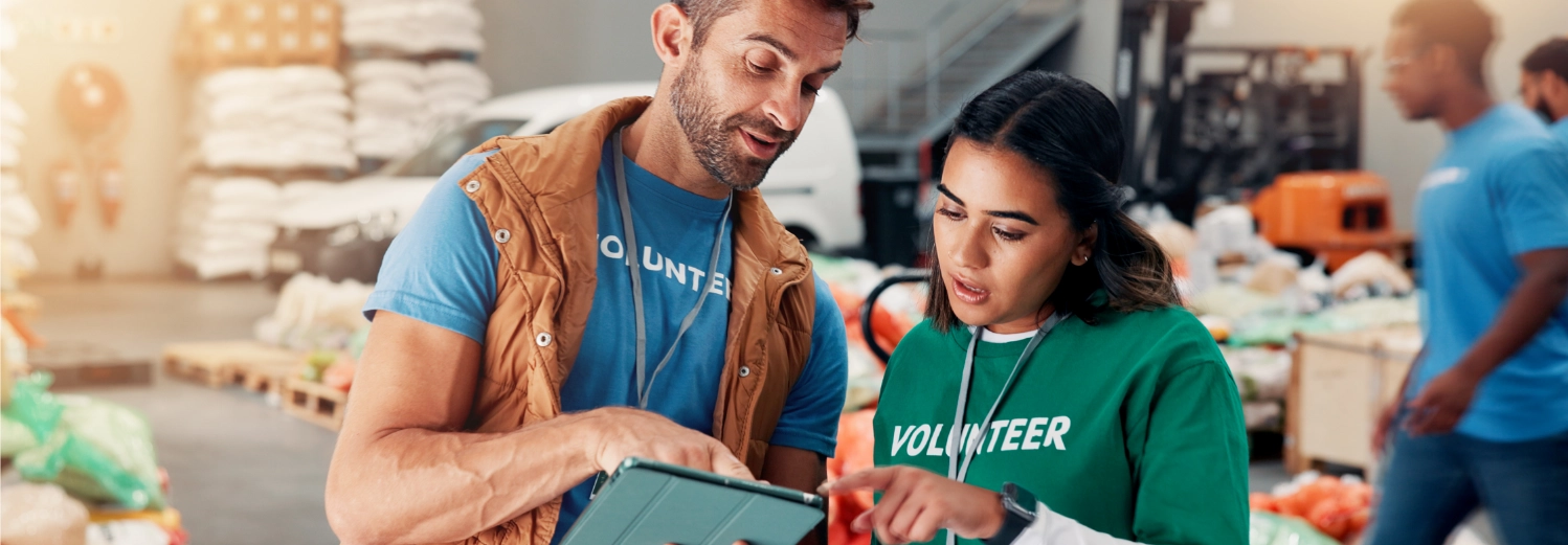Volunteer team members using tablet for coordinating food distribution and donation management at community food bank