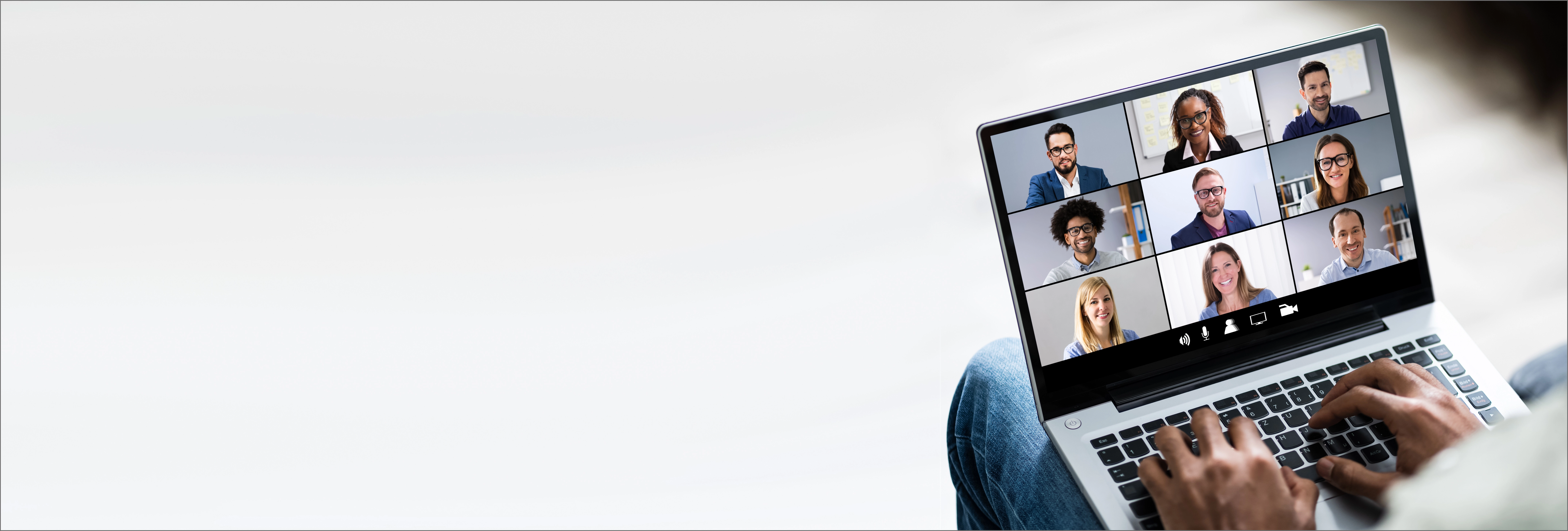 Person typing on laptop during virtual team video conference call with diverse group of professionals in grid view